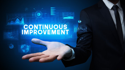 Hand of Businessman holding CONTINUOUS IMPROVEMENT inscription, business success concept