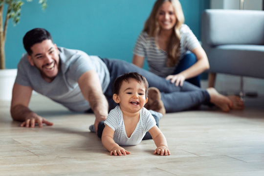Pretty young parents playing with baby son while sitting on the floor at home.