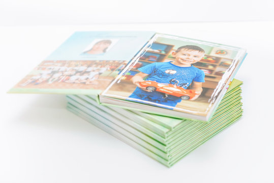 graduation photo album of a smiling boy from kindergarten. memorable children's photos are printed in the album. albums on a light background