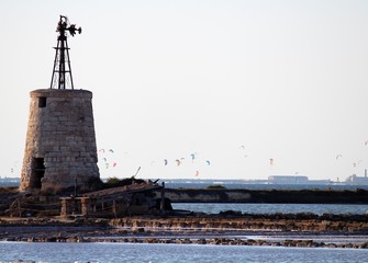 tower in the foreground on the sea with sportsmen doing kitesurfing in the background