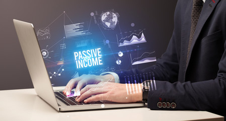 Businessman working on laptop with PASSIVE INCOME inscription, new business concept