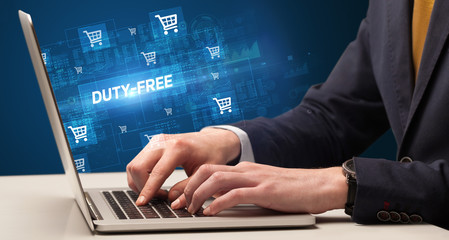 Businessman working on laptop with DUTY-FREE inscription, online shopping concept