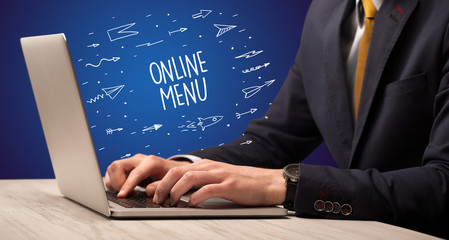 Businessman working on laptop with ONLINE MENU inscription, online shopping concept