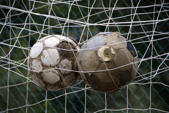 old soccer balls in  soccer goal net