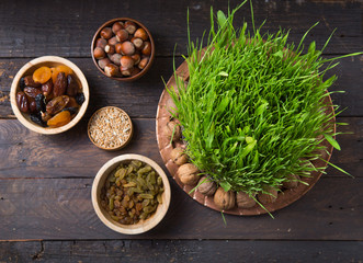 Fototapeta na wymiar Happy Nowruz holiday background. Celebrating various dried fruits, nuts, seeds, light background with green grass wheat, copy space top view