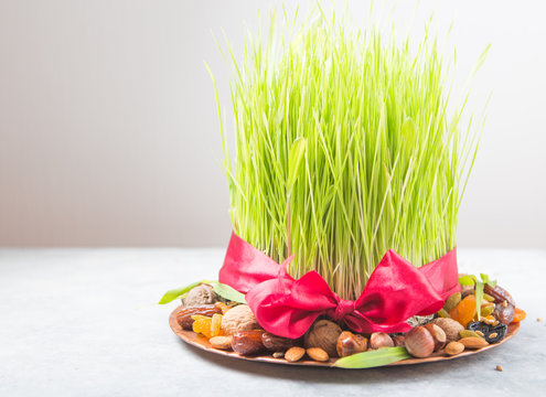 Happy Nowruz holiday background. Celebrating  various dried fruits, nuts, seeds, light background with green grass wheat, copy space top view