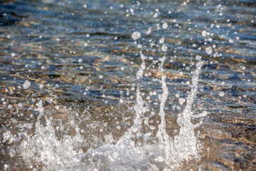 Fototapeta na wymiar Water spray produced by wave on beachline, selective focus on water splashes