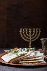 Passover, the Feast of Unleavened Bread, matzah bread and red wine glasses on the shinny round metal tray.