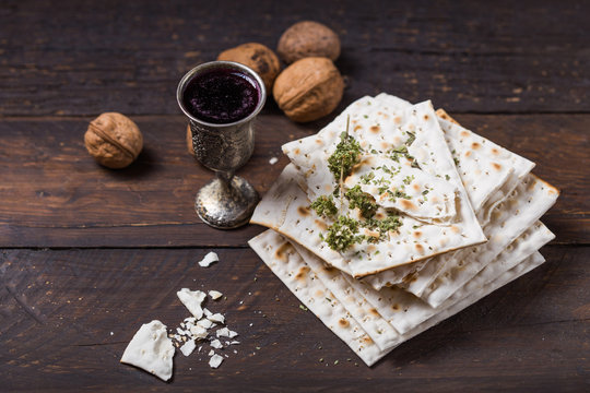 Red kosher wine with a white  matzah or matza on a vintage wood background presented as a Passover seder meal with copy space.