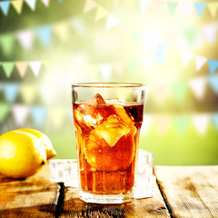 Fresh cold ice tea in glass and blurred landscape of park.Copy space for your composition. 