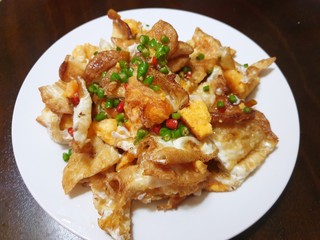 Thai food style, Top view of spicy fried egg salad with chili slices on white plate on wooden table as a background in restaurant, This food is most popular Thai food