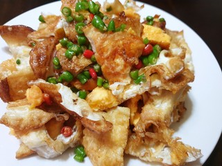 Thai food style, Top view of spicy fried egg salad with chili slices on white plate on wooden table as a background in restaurant, This food is most popular Thai food