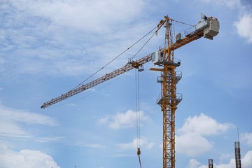 Fototapeta na wymiar Looking up of tower crane on sky and cloud with sun shining as a background in the construction site, Space for text in template, Industrial skyline