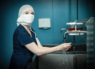 Nurse in medical mask washes hands