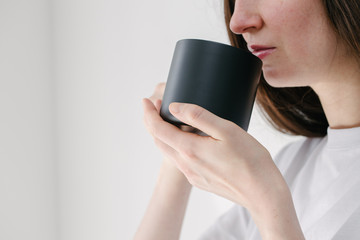 Black metal cup for tea and coffee in woman hand over white background for cup or mug mock up