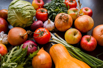 onions, garlic, tomato, greens, parsley, arugula, cabbage, apples, beetroot, carrots, pumpkin, lie on a wooden table