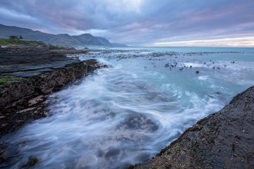 A beautiful early morning seascape photographed on a stormy day at sunrise in Hermanus, South Africa.