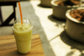 Melon juice in plastic cup on wood table