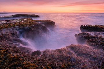 Obraz premium A beautiful golden late evening seascape with rocks in the foreground, photographed on a stormy day after sunset in Arniston, South Africa.