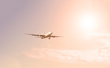 Airplane in the sky with clouds and white sun. Passenger transport