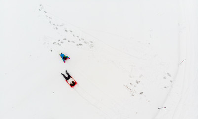 Top down view of two people tobogganing in snow