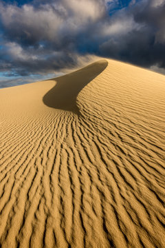 A dramatic vertical dune landscape taken on a cloudy stormy afternoon in Arniston, South Africa. The sand on the top of the peak was being blown by the strong wind.