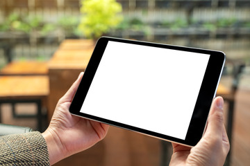 Mockup image of a woman sitting and holding black tablet pc with blank white desktop screen