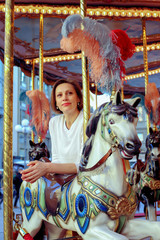 Fototapeta na wymiar Woman riding on a traditional vintage carousel in a city park