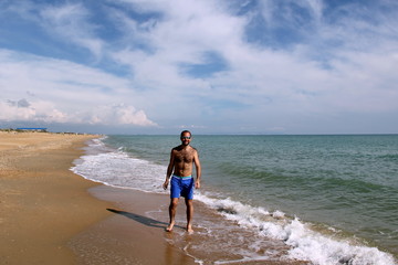 Young man on the sea in blue shorts