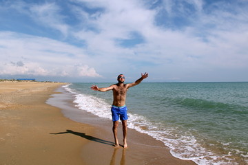 Obraz na płótnie Canvas Young man on the sea in blue shorts