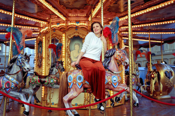 Woman riding on a traditional vintage carousel in a city park