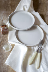 Two empty serving white plates with forks and napkin. rustic wooden background. minimal style, top view. Table setting.