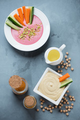 Hummus with carrot and cucumber slices on a grey concrete surface, studio shot, view from above