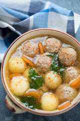 Soup with meatballs, potato balls, carrots and greens, selective focus, close-up, vertical shot