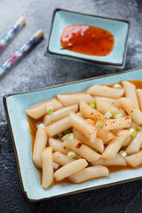 Spicy korean topokki or rice cakes served on a turquoise plate, selective focus, closeup