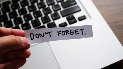 Don't Forget message concept written post it on laptop keyboard.