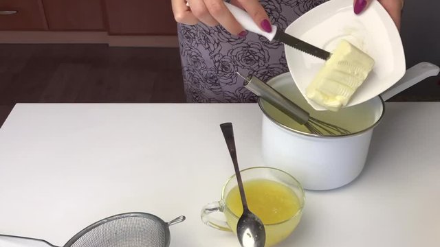 Girl mixes ingredients for lemon kurd in a saucepan. After that, he puts it on a gas stove and stirs during cooking.