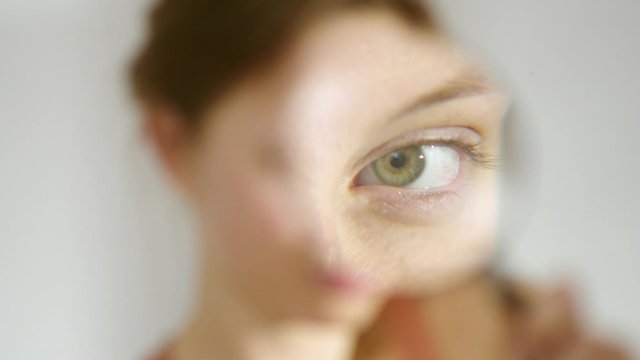 Girl looking through a magnifying glass. Beautiful girl with loupe zooming her eye