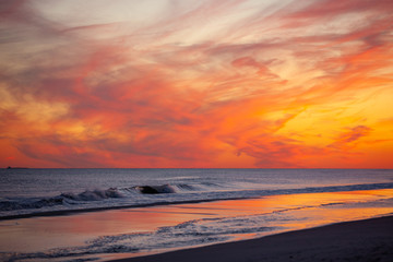 Vibrant pink and orange sunset over small waves breaking on the beach. Jones Beach, Long Island New...