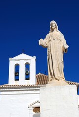 Fototapeta na wymiar View of Our Lady of Remedies hermitage with a statue in the foreground, Velez Malaga, Spain.