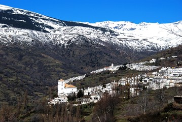Fototapeta na wymiar View of the towns of Bubion and Capileira (to the rear) seen against a snow capped backdrop of the Sierra Nevada Mountains, Bubion, Spain.