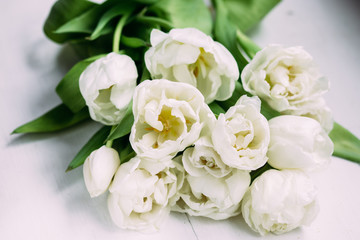 Bouquet of white tulips on a wooden background with space for text. 