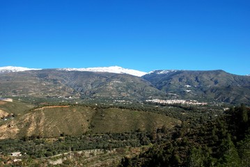 Fototapeta premium View of the town and countryside in the Vale of Lecrin with views towards the snow capped Sierra Nevada mountains, Orgiva, Spain.