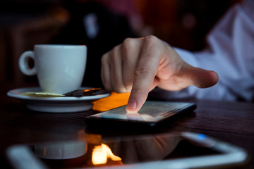 Fototapeta na wymiar Finger of a Man Touching Phone Screen at the Table in the Restaurant