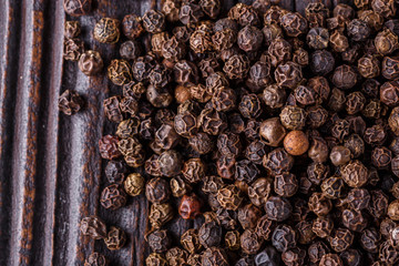 aromatic black pepper on a dark wooden rustic background