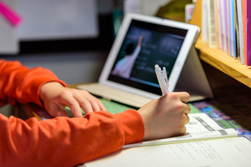 マスクをした子供が自宅でタブレット学習するシーン