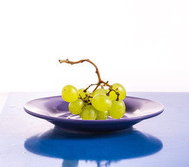 A bunch of green grapes on a lilac plate