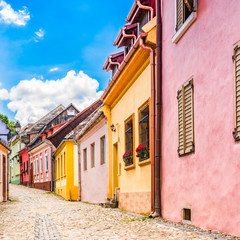 Fototapeta na wymiar Old medieval cobblestone stree with colorful houses in Sighisoara, Transylvania, Romania