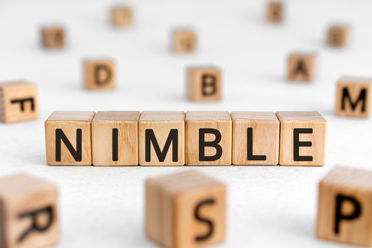 Nimble - word from wooden blocks with letters, quick agile nimble concept, random letters around white background