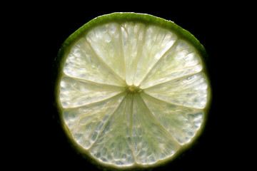 Lime slice backlit isolated on black background. green fresh limes cut close-up. Design element - Powered by Adobe